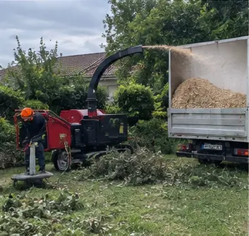 Broyeur transformant des branches coupées en copeaux dans un jardin