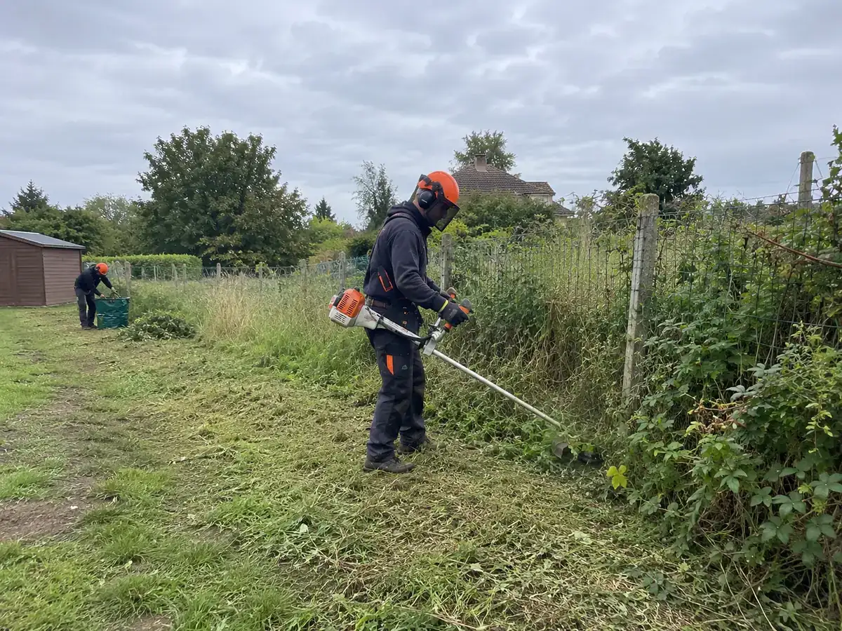 Photo d’illustration : débroussaillage d’herbes hautes le long d’une clôture